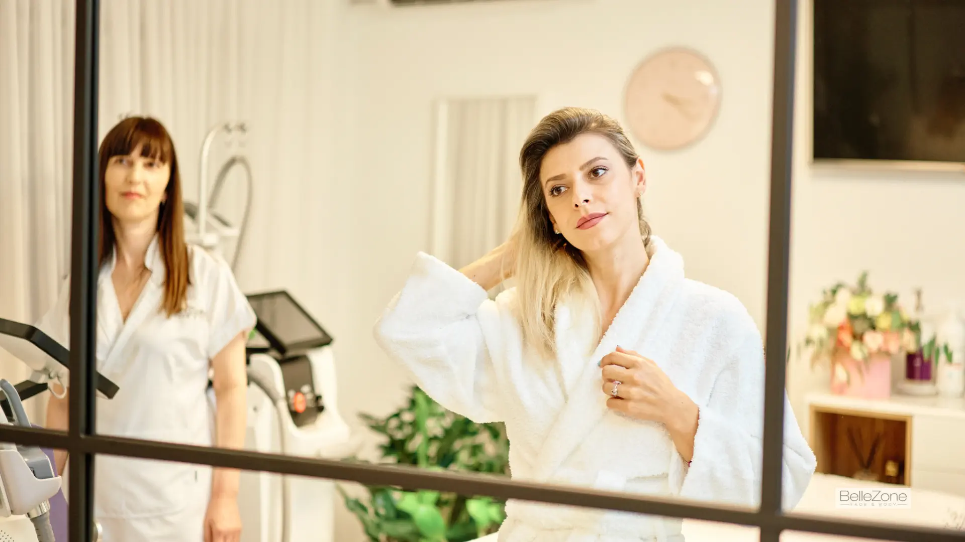 A woman in a green scrub suit is treating client's face with a machine.